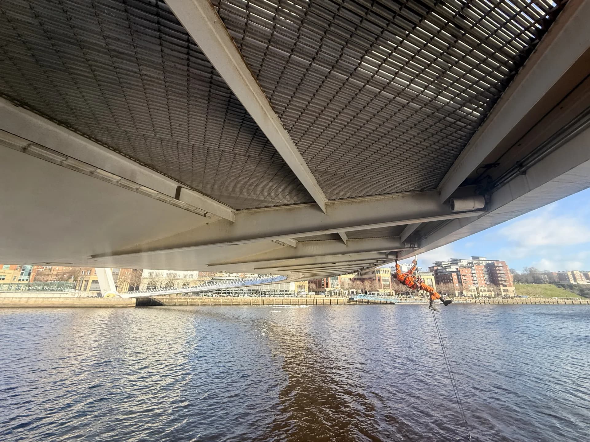 Technician working beneath the bridge deck over the river